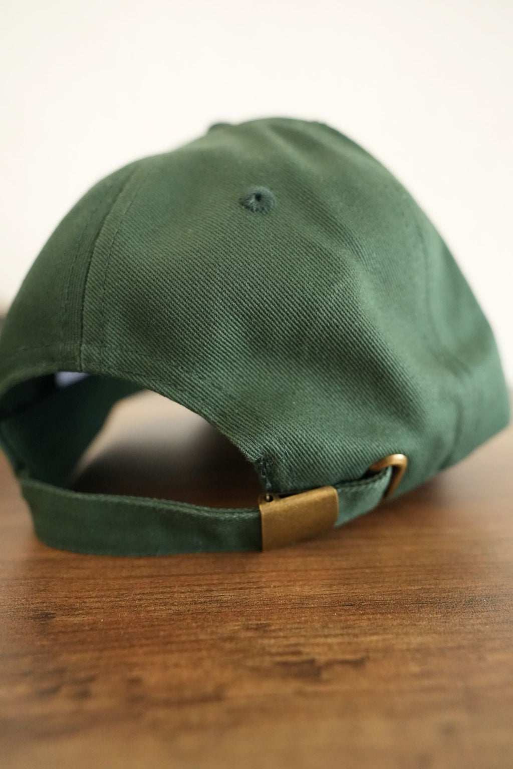 Green cap with a gold buckle on a wooden surface