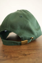 Green cap with a gold buckle on a wooden surface